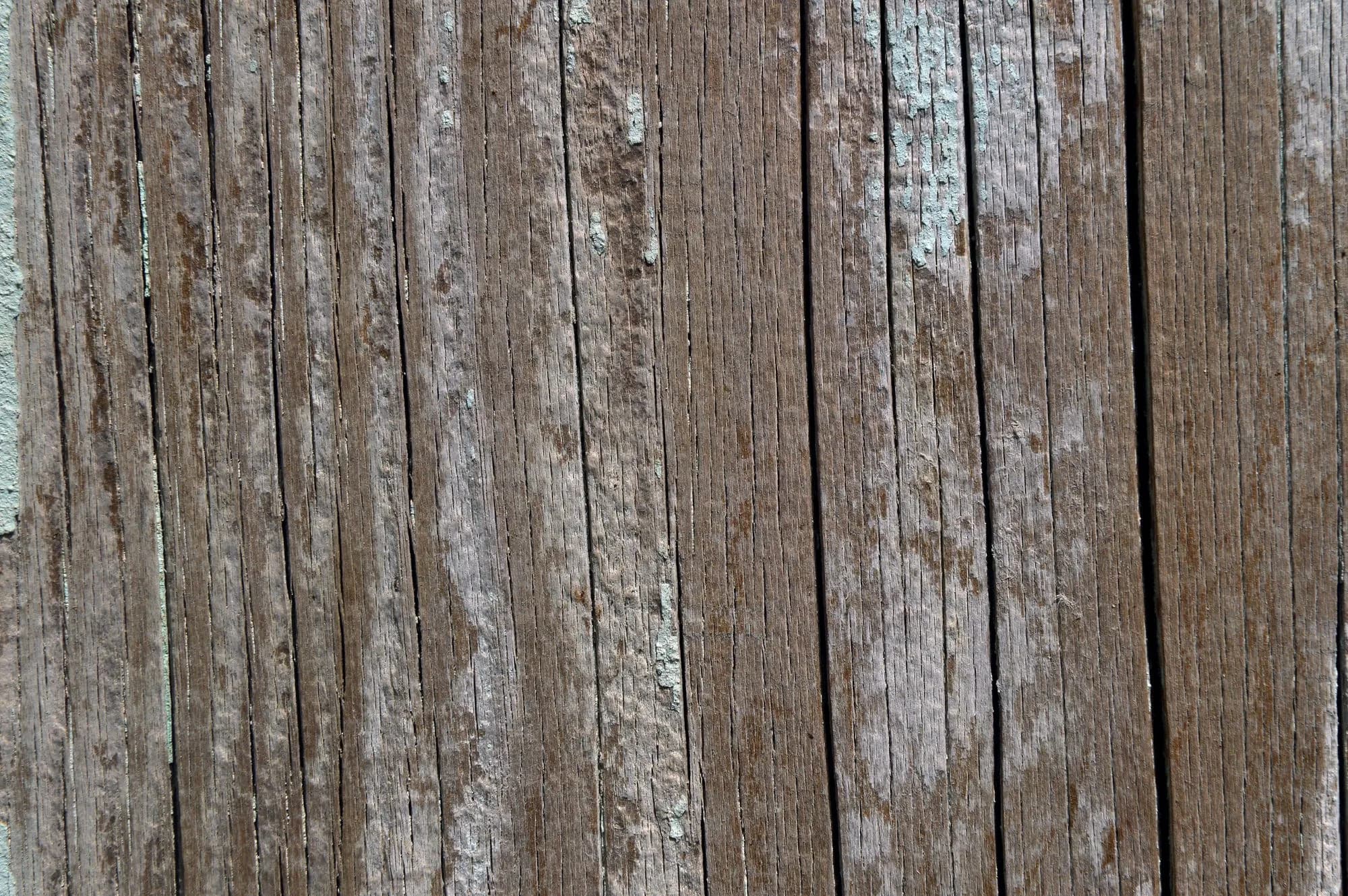 Close-up of an aged wooden deck board surface showing natural grain, texture and weathered brown tones