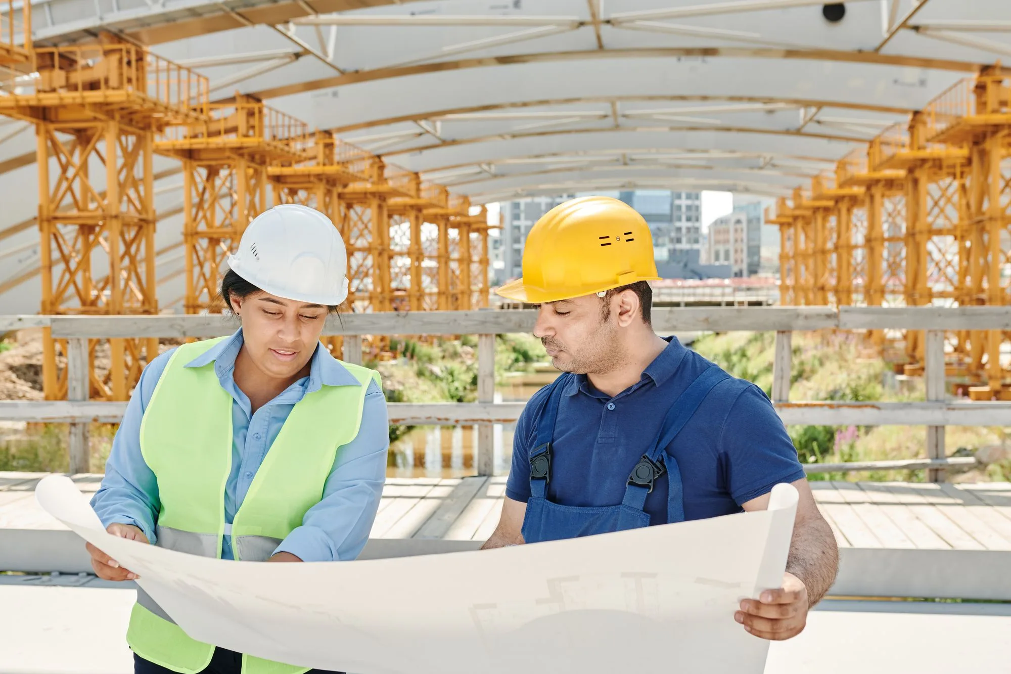 Construction team in safety gear reviewing blueprints outdoors, the kind of planning stage where you find out if you need a permit to build a deck