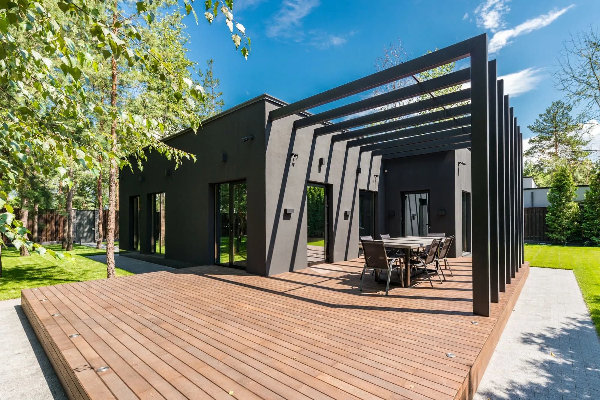 Stylish wooden deck with a dining set surrounded by greenery, the kind of build this deck cost guide helps you budget for