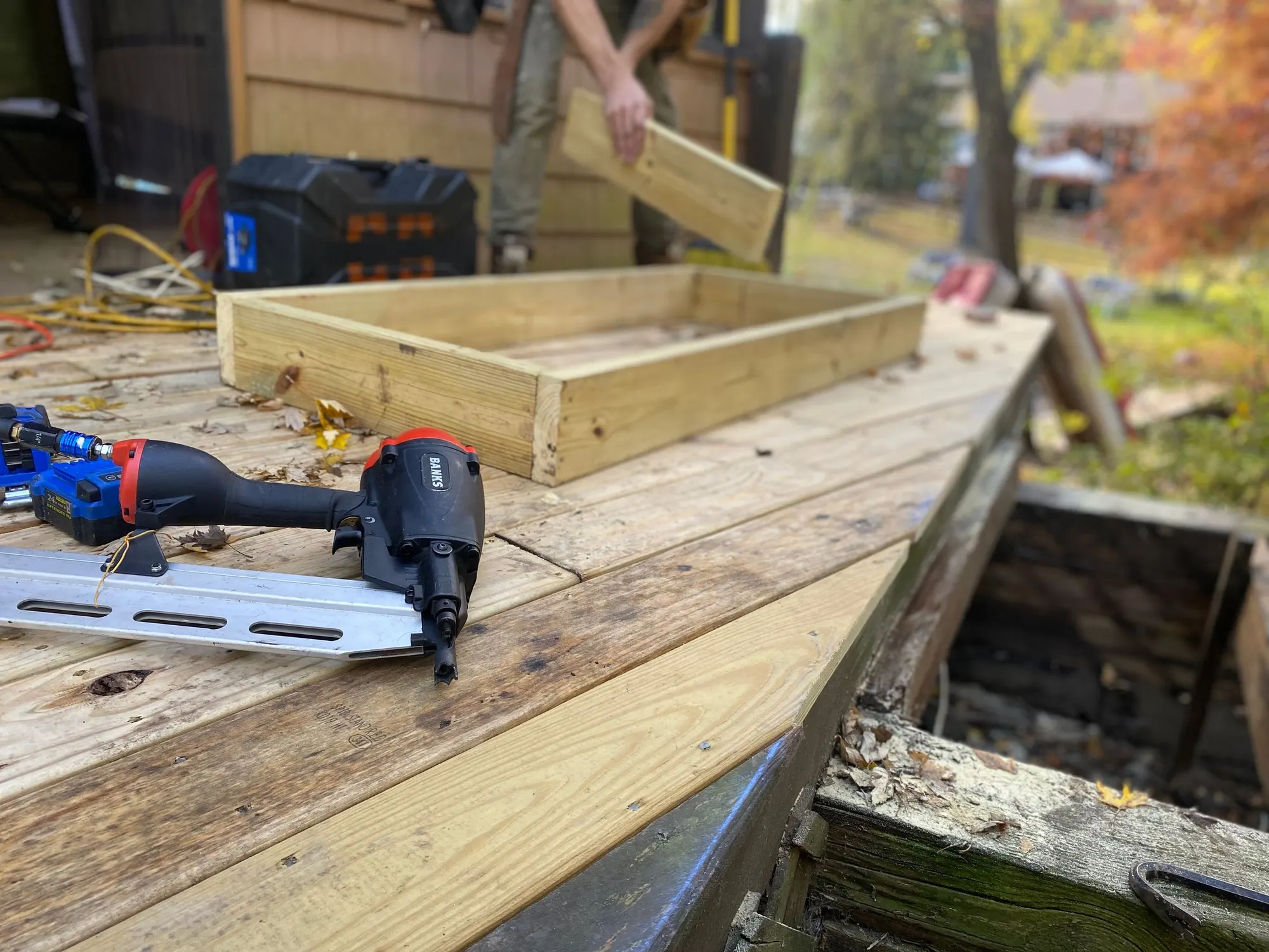 A carpenter fastening deck joists with a framing nailer